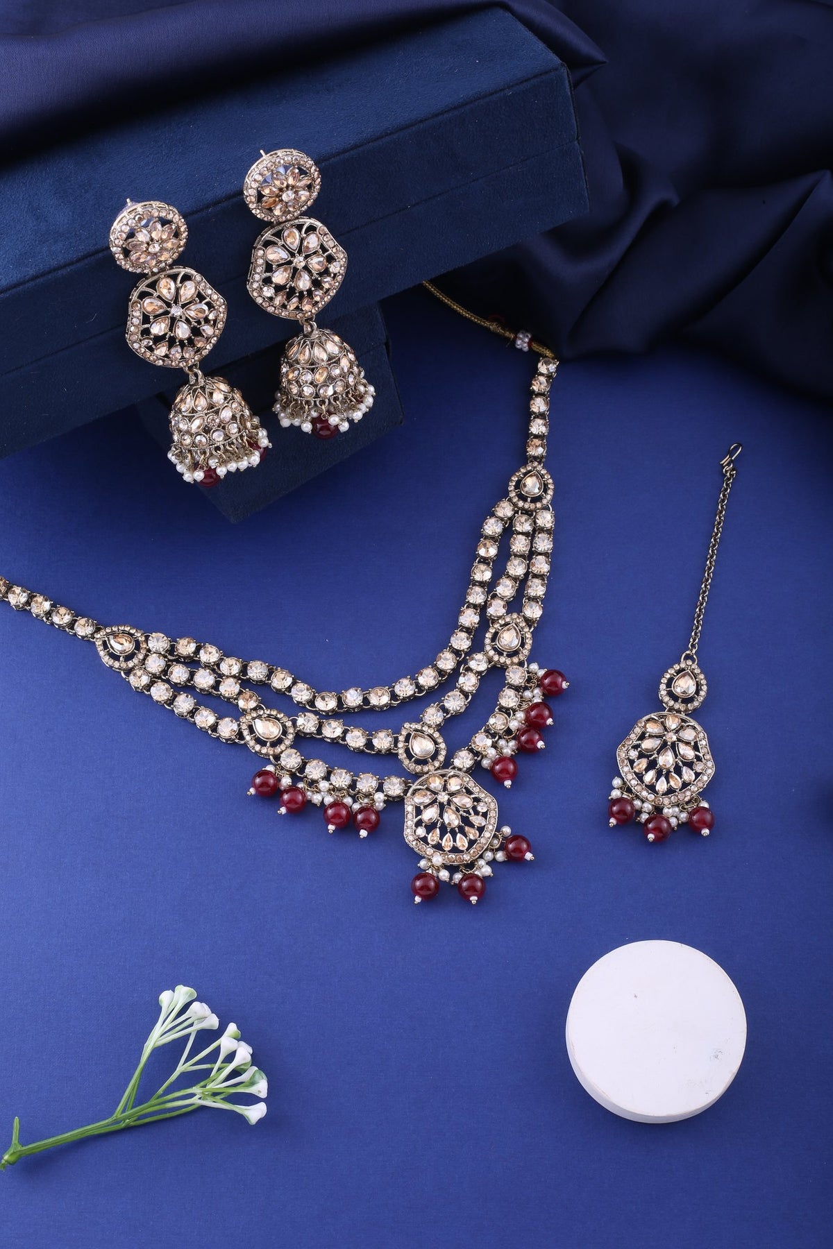 Ruby Red Three Layer Polki Necklace Set with Jhumkas & Maang Tikka, styled flat lay